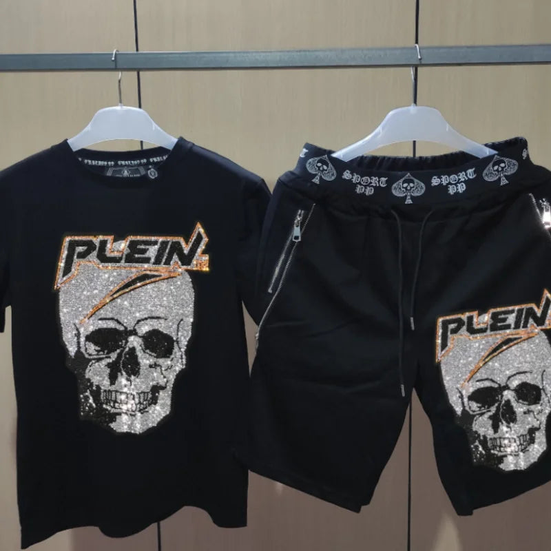 Black hoodie and t-shirt set with skull design and 'Plein' branding on hangers against a neutral background.