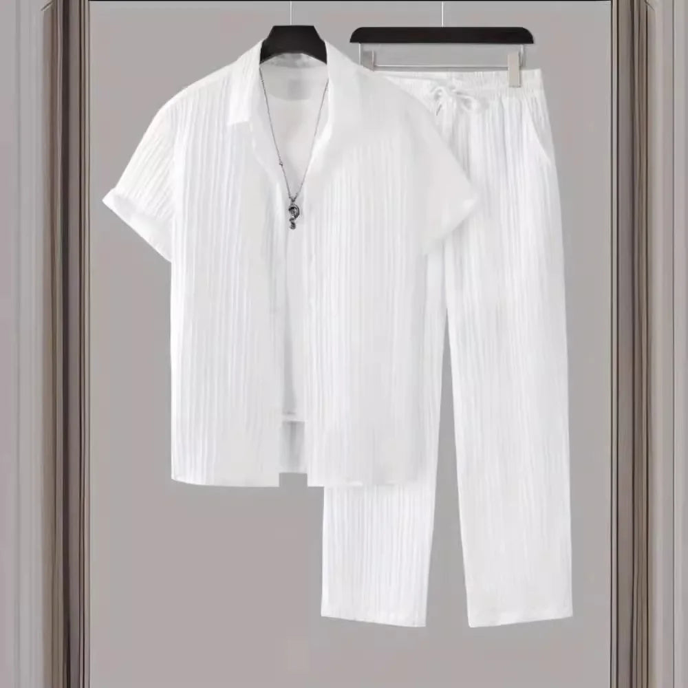 White pleated shirt and pants set on hangers against a neutral background