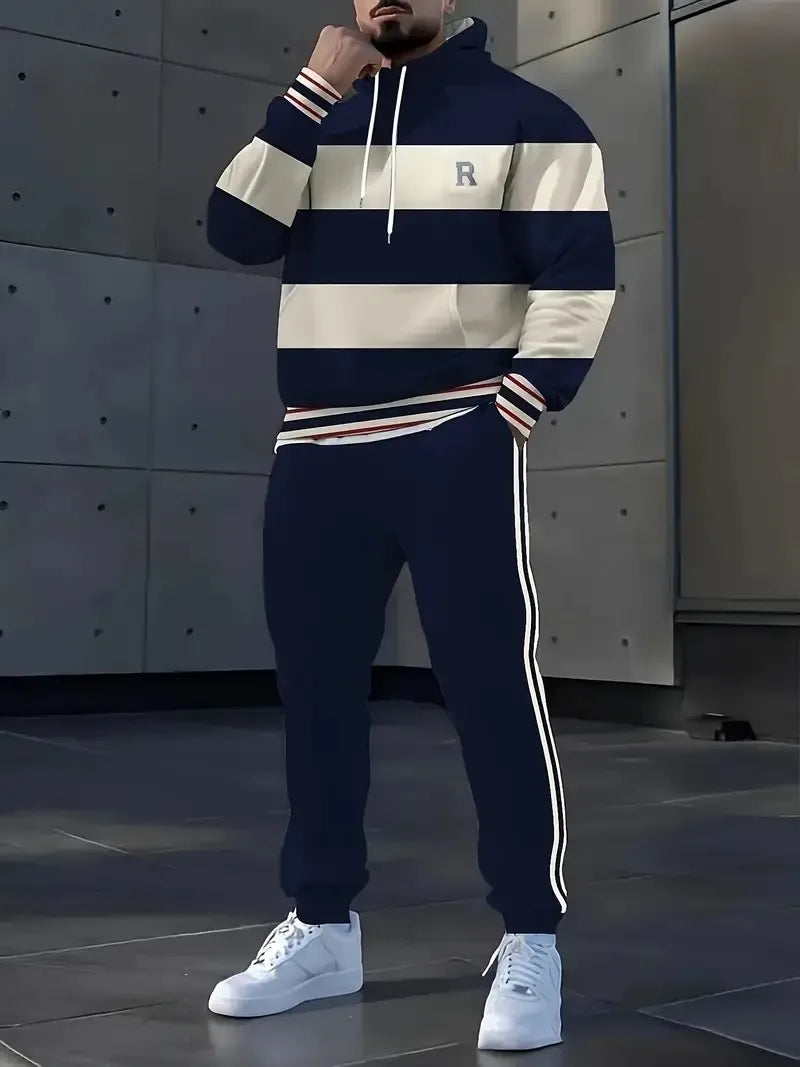 Person wearing a navy and white striped hoodie and pants with a logo, standing against a metallic wall.