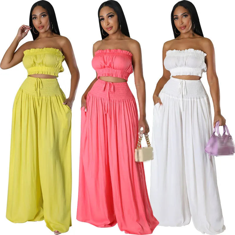 Three women wearing strapless tops and wide-leg pants in yellow, pink, and white.