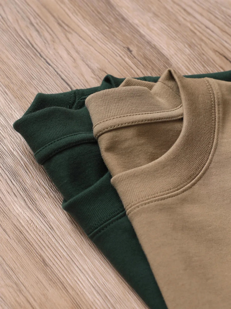 Folded brown and green sweatshirts on a wooden surface