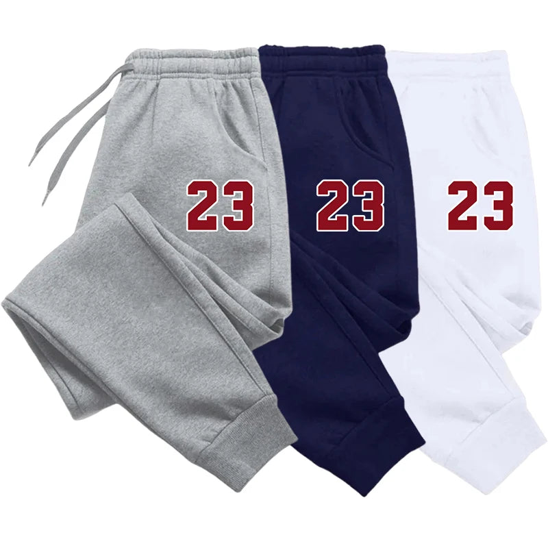 Three pairs of sweatpants in gray, navy, and white with the number 23 printed on them.