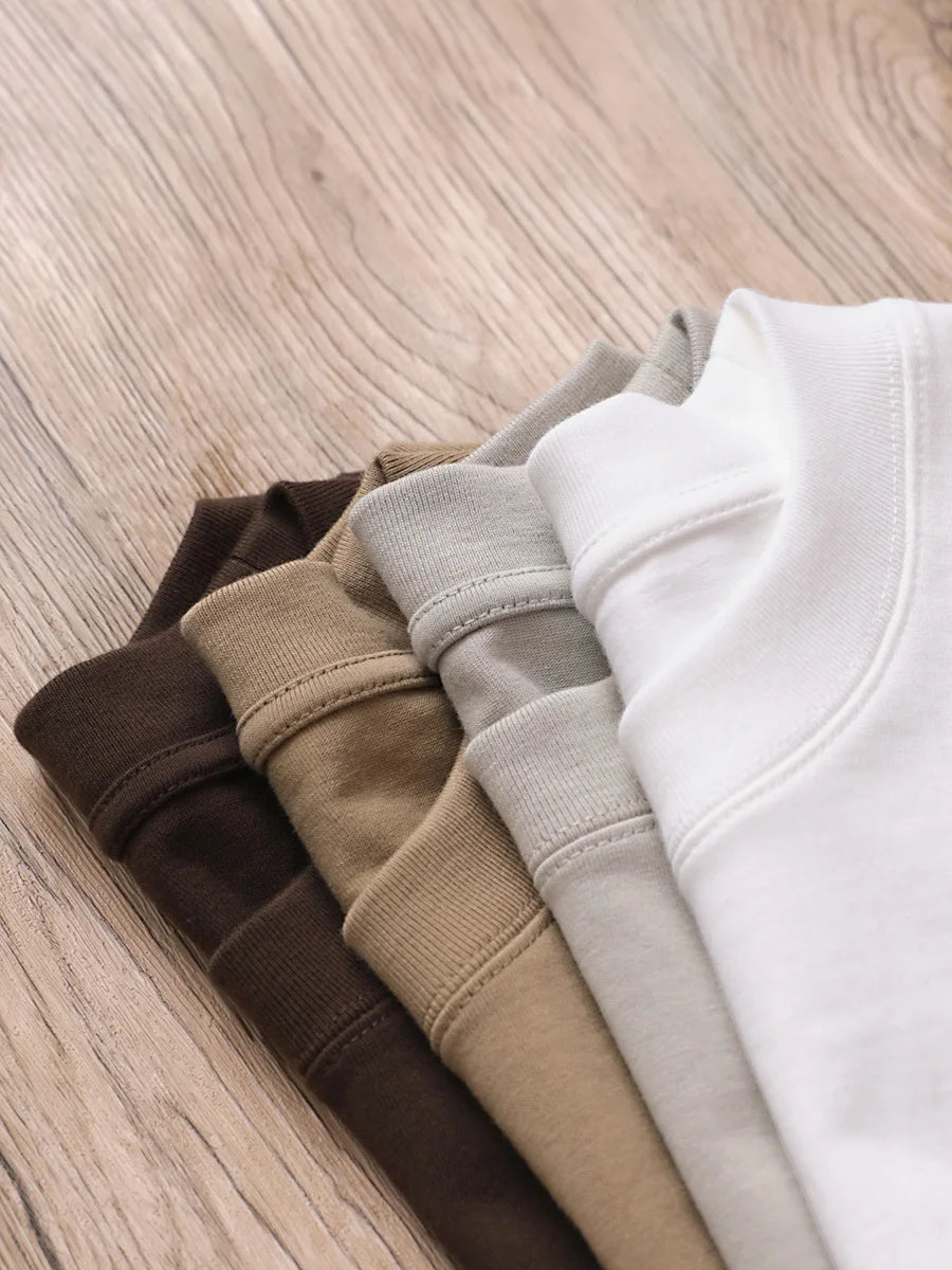 Folded sweatpants in brown, beige, gray, and white on a wooden surface