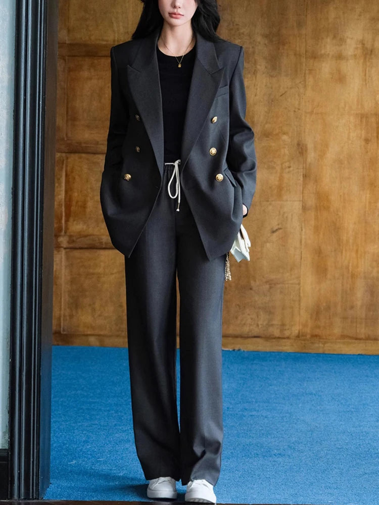 Person wearing a black suit with gold buttons on a wooden floor and blue carpet.