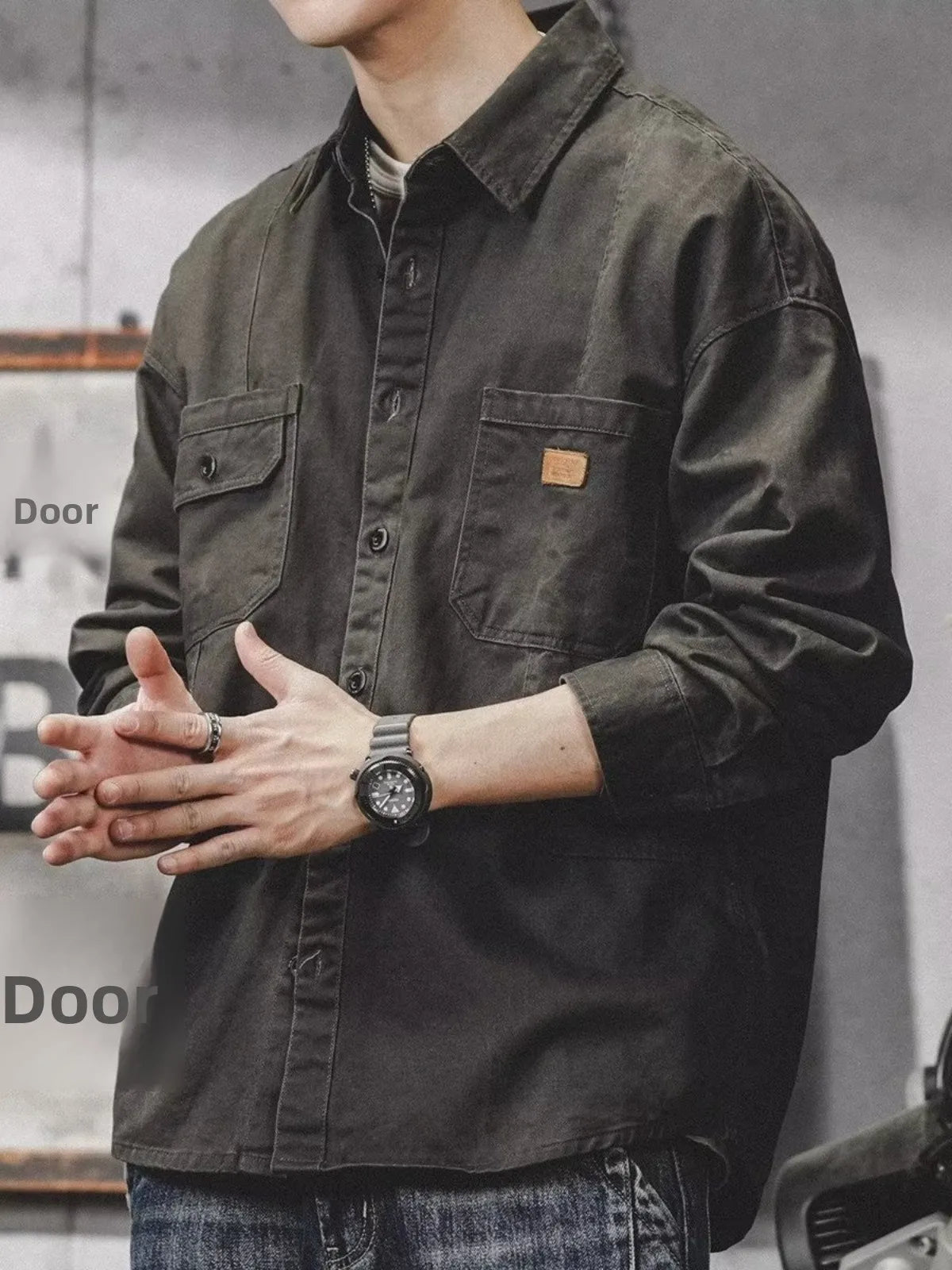 Person wearing a dark green jacket with a brand logo, standing against a blurred background.